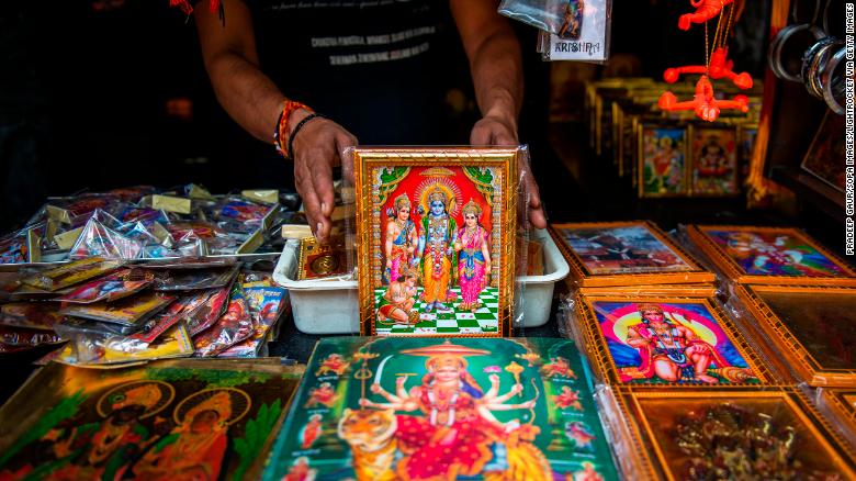 A shopkeeper is seen showing a variety of colourful frames of Lord Rama. 