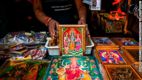 A shopkeeper is seen showing a variety of colourful frames of Lord Rama. 