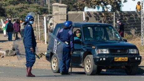Zimbabwe police ask for travel documents at a road block the country on July 31 where they were deployed following a ban on anti-government protests. 