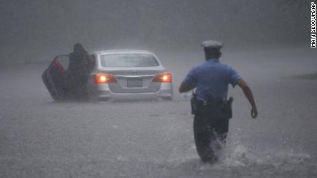 A Philadelphia police officer rushes to help a stranded driver Tuesday during Tropical Storm Isaias.