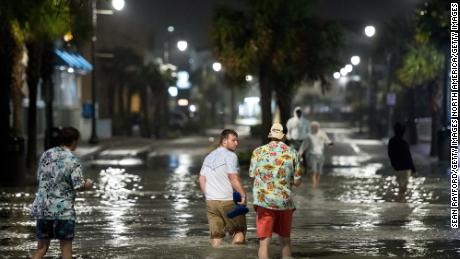 People walk through floodwaters Monday in Myrtle Beach, South Carolina.