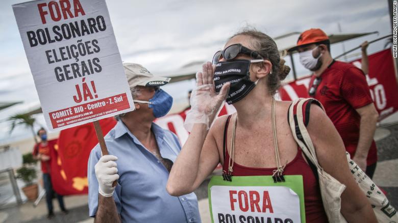 ผู้ประท้วงถือป้ายที่เขียนว่า "ไปให้พ้น Bolsonaro เลือกตั้งทั่วไปเดี๋ยวนี้!"  ระหว่างการชุมนุมต่อต้านประธานาธิบดี Jair Bolsonaro และผู้ว่าการริโอเดอจาเนโร Wilson Witzel ท่ามกลางการระบาดของ coronavirus (COVID-19) ที่หาด Copacabana เมื่อวันที่ 28 มิถุนายน 2020 ในเมืองริโอเดจาเนโร ประเทศบราซิล