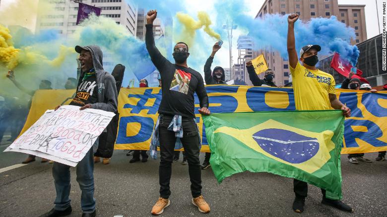 ผู้ประท้วงสวมหน้ากากอนามัยยกกำปั้นที่ถนน Paulista ระหว่างการประท้วงท่ามกลางการระบาดของไวรัสโคโรน่า (โควิด-19) เมื่อวันที่ 14 มิถุนายน 2020 ในเซาเปาโล ประเทศบราซิล