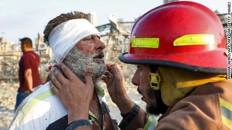 A wounded man is checked by a fireman near the scene of an explosion in Beirut on August 4, 2020. 