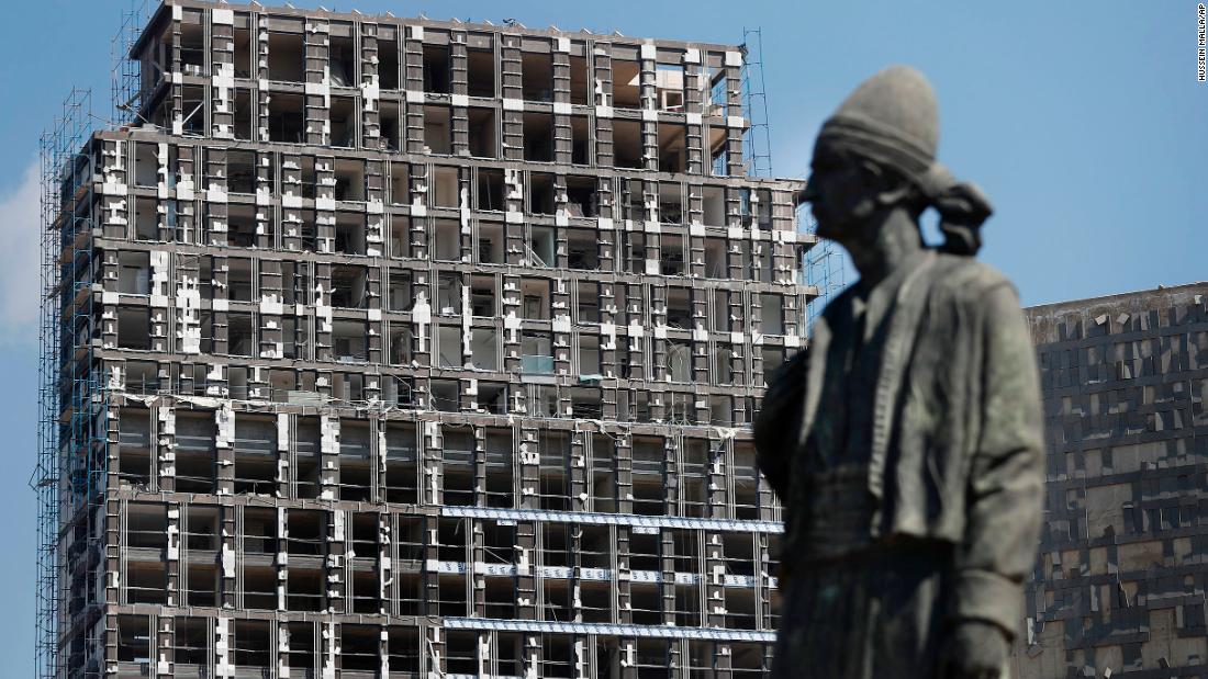 A statue representing the Lebanese expatriate is seen in front of a building that was damaged by the explosion.