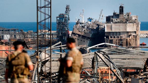 Lebanese soldiers stand guard in front of destroyed ships.