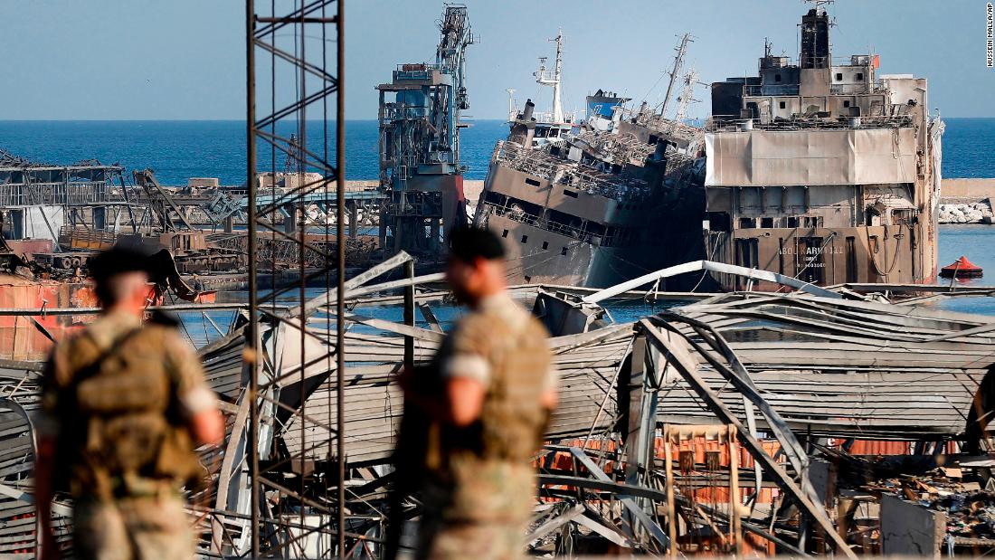 Lebanese soldiers stand guard in front of destroyed ships.