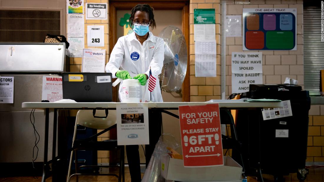 Poll worker Debra Moore sanitizes her workspace during a primary election in Detroit on August 4.