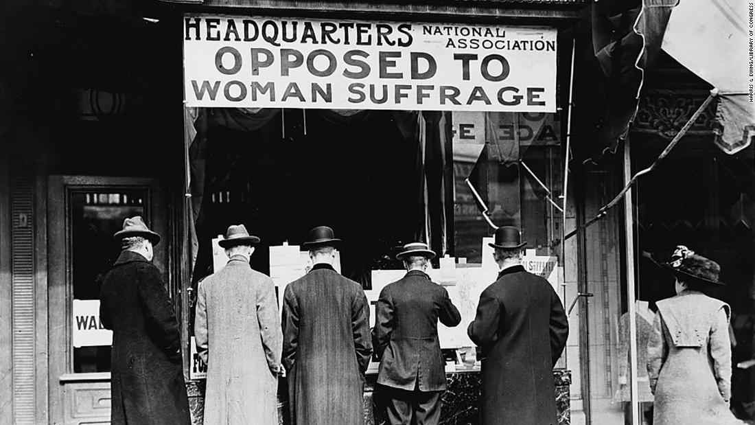 Photograph shows men looking at material posted in the window of the National Anti-Suffrage Association headquarters