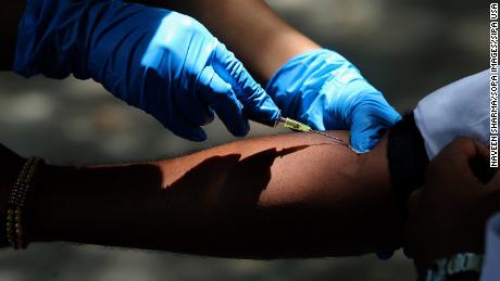 A medical Personnel collecting a blood sample from a man during the tests.