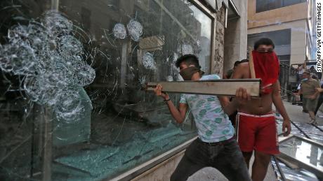 A Lebanese demonstrator breaks a shop window during clashes with security forces in Beirut.