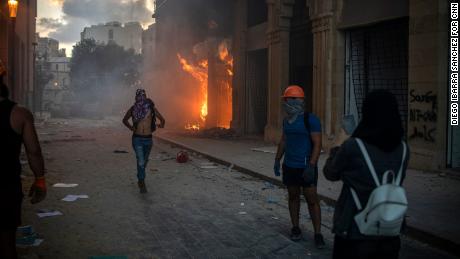 Protesters take pictures of a building set on fire.