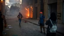 Protesters take pictures of a building set on fire.