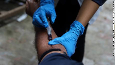 Un trabajador médico toma una muestra de sangre de un hombre en la India. 