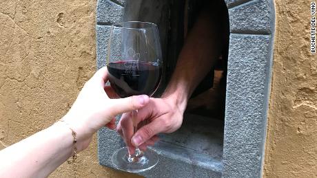 A glass of red being served through a wine window in Florence.  