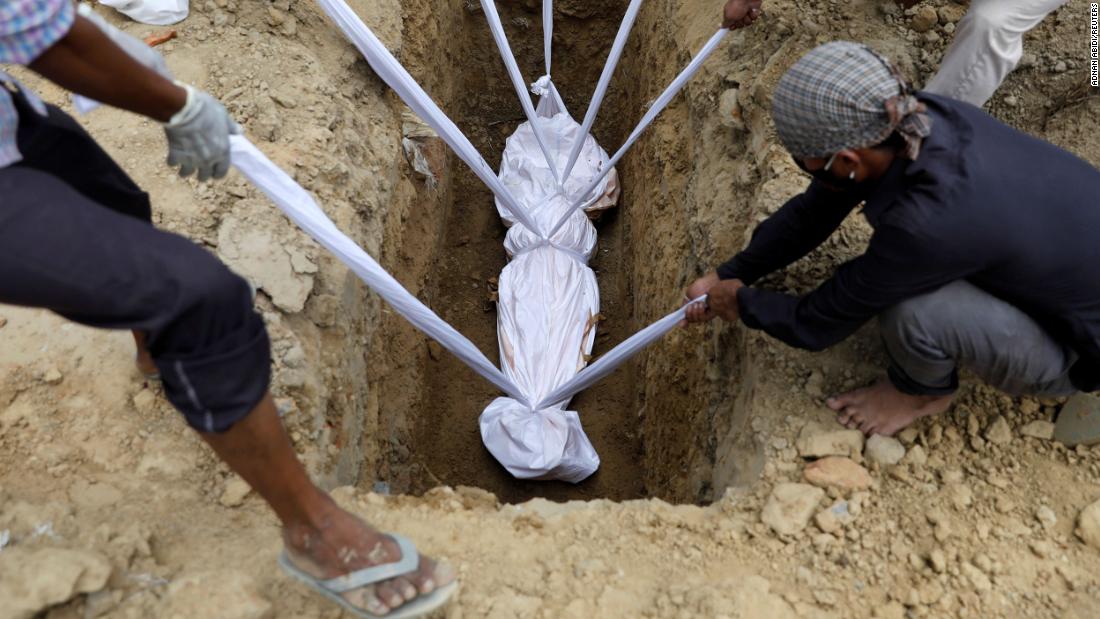 A coronavirus victim is lowered into the ground during her funeral in New Delhi on August 7.