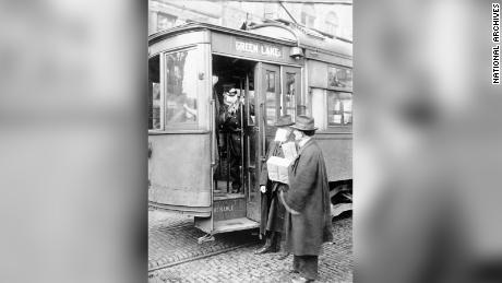 A street car conductor in Seattle not allowing passengers aboard without a mask in 1918.