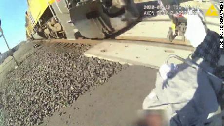 An officer rescued a man in a wheelchair stuck on a railroad track.  Her bodycam video shows the rescue