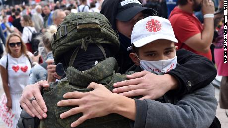 Protesters in Minsk embrace a Belarus law enforcement officer during a rally against President Alexander Lukashenko, who is accused of falsifying the polls in Sunday&#39;s election.