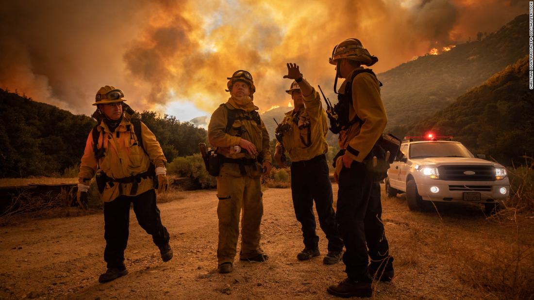 Firefighters make an escape plan as the Lake Fire burns a hillside on August 12, 2020.