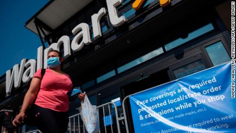 A woman wearing a facemask walks past a sign informing customers that face coverings are required in front of a Walmart store in Washington, DC on July 15, 2020. - Walmart will require shoppers to wear face masks starting next week, the US retail giant announced on July 15, joining an increasing number of businesses in mandating the protection amid the latest spike in coronavirus cases. (Photo by Andrew Caballero-Reynolds/AFP/Getty Images)