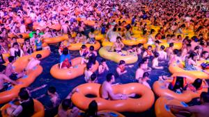 This photo taken on August 15, 2020 shows people watching a performance as they cool off in a swimming pool in Wuhan in China's central Hubei province. 