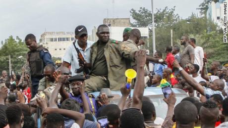 Armed Malian soldiers and policemen ride on the back of a pick-up truck as they arrive at Independence Square in Bamako on Tuesday following news of the coup.