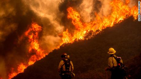 Flames from the River Fire crest a ridge Monday as firefighters Ian Johnson, right, and Capt. Mike Campbell protect a home in Salinas, California.