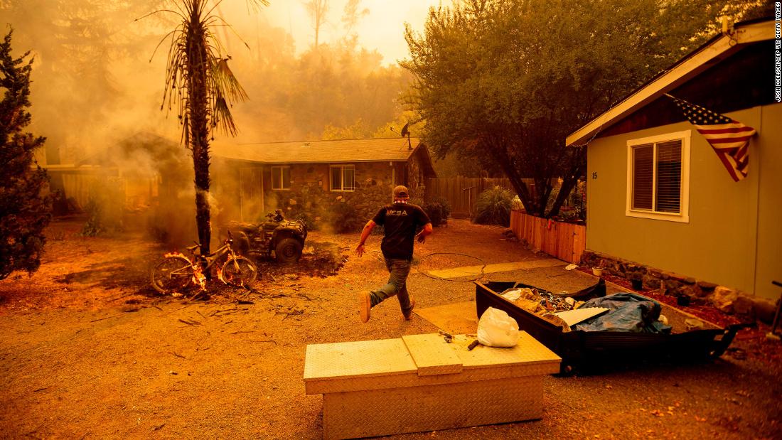 A resident runs into a home to save a dog while flames from the Hennessy Fire close in near Lake Berryessa on August 18, 2020.