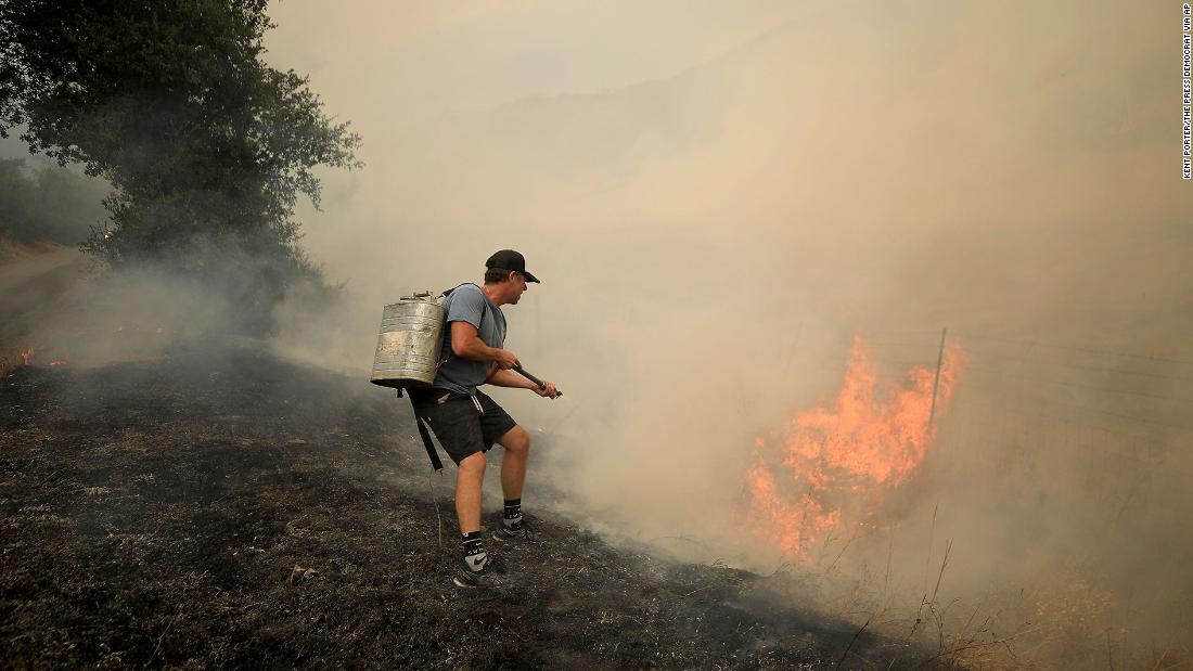 Tony Leonardini works on a spot fire as thunderstorm winds fan the Hennessy Fire in Napa County on August 17, 2020.