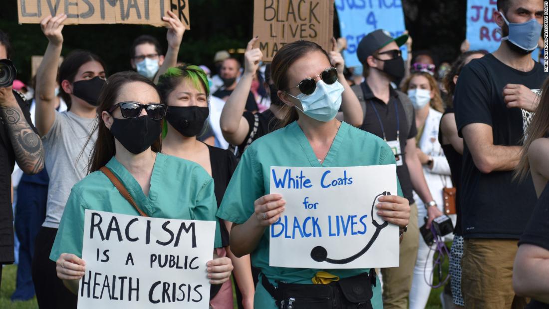 Medical workers hold signs during a rally, organized by a group named White Coats for Black Lives, on June 6 in New York.