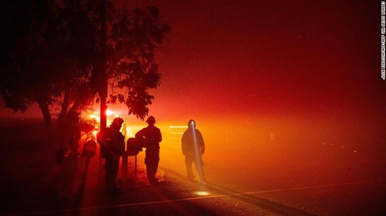 Firefighters monitor flames Wednesday as they approach a home in the valley area of Vacaville, California.