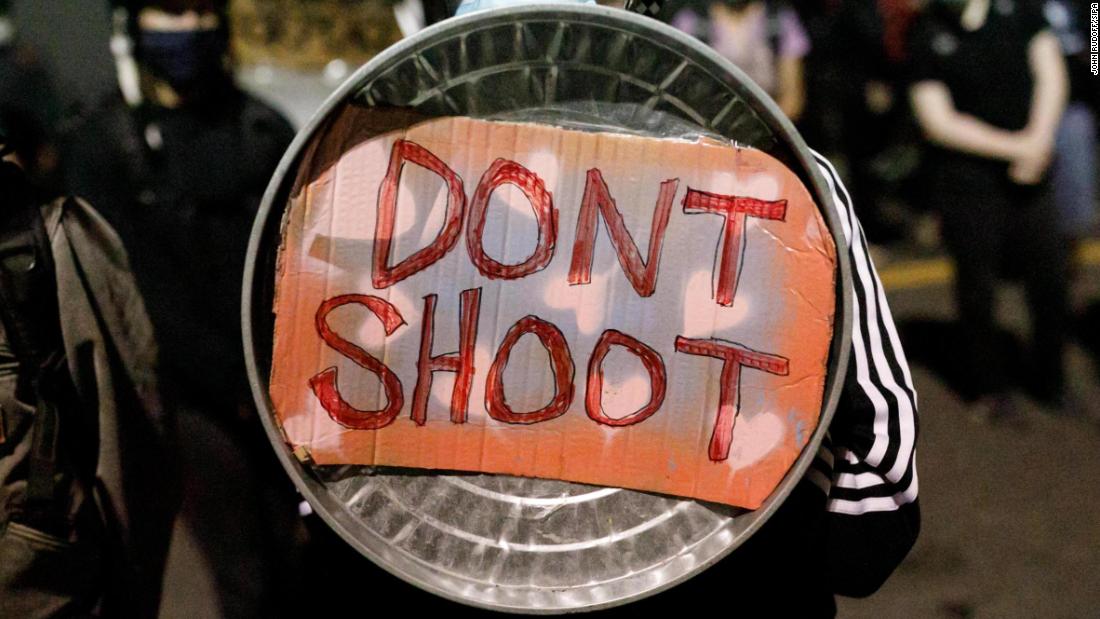 A demonstrator uses a shield for protection on August 19.