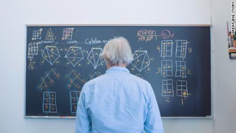 Dave Bayer stands in front of a blackboard covered in Hagoromo chalk.