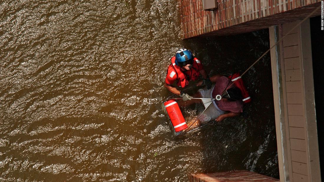 Coast Guard Petty Officer 2nd Class Scott D. Rady pulls a pregnant woman from her flooded New Orleans home.