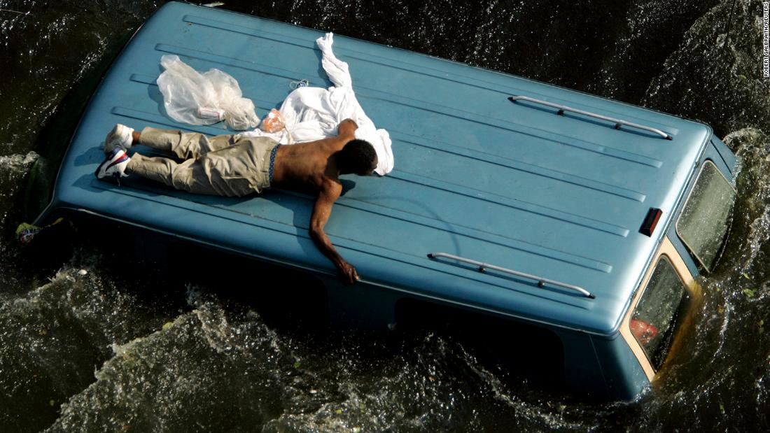 A man clings to the top of a vehicle in New Orleans before being rescued by the Coast Guard.