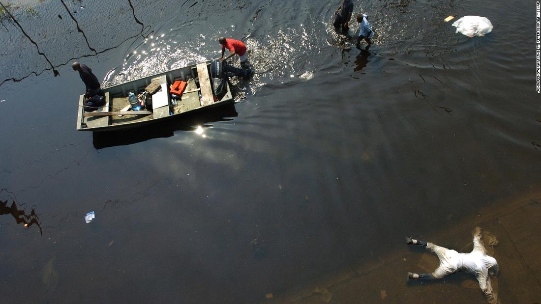 A dead body is seen in the foreground as people push a boat outside the Superdome on September 2, 2005.