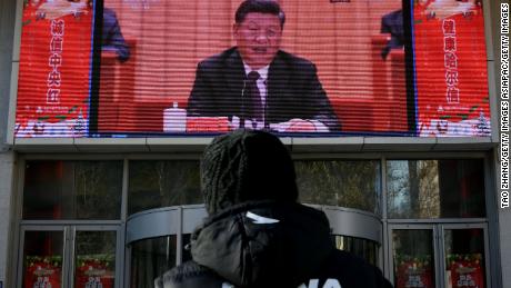A man stands and watches a large screen during President Xi Jinping&#39;s speech commemorating the 40th anniversary of China&#39;s policy of reform and opening on December 18, 2018.