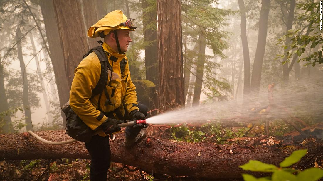 Karol Markowski of the South Pasadena Fire Department hoses down hot spots while battling the CZU Lightning Complex fires in Boulder Creek, California, on August 22, 2020.