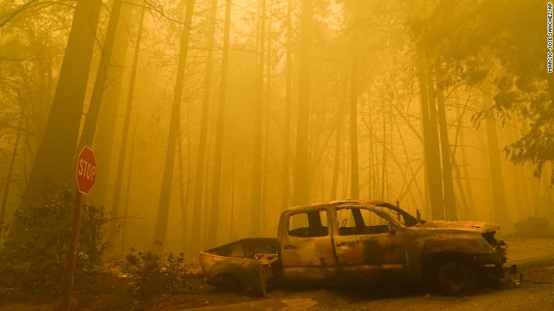 A burned out vehicle is left in front of a fire- ravaged residence as smoke fills the sky on Saturday, August 22, in Boulder Creek, California.