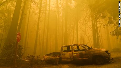 A burned out vehicle is left in front of a fire- ravaged residence as smoke fills the sky on Saturday, August 22, in Boulder Creek, California.