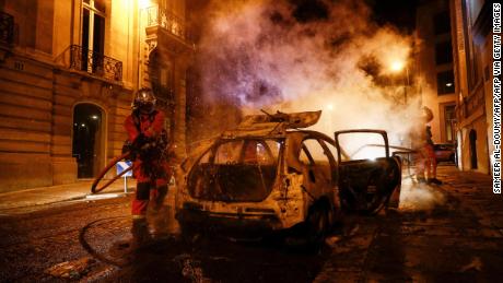 Firefighters extinguish a burning car near the Champs-Élysées following PSG&#39;s Champions League final defeat.