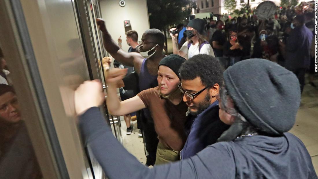 People pound on the door of the Kenosha Police Department.