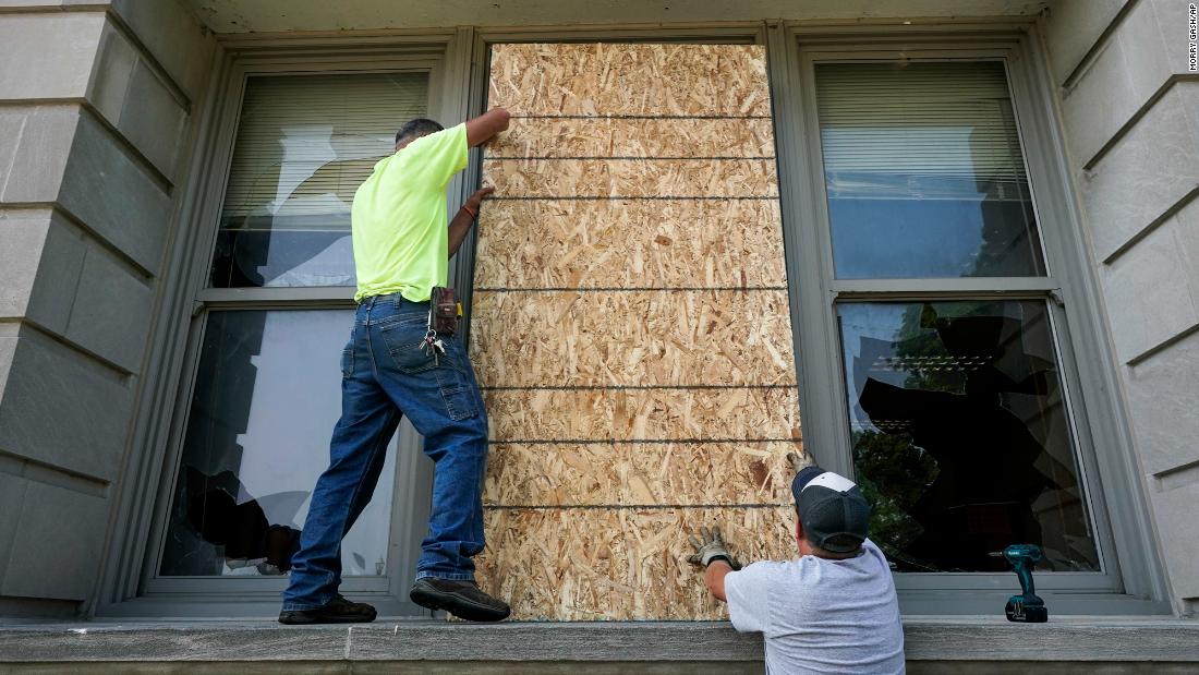 Joe Loewen and Dan Noonan put boards over a broken window at the Harborside Academy. The windows were broken during protests on Sunday, August 23