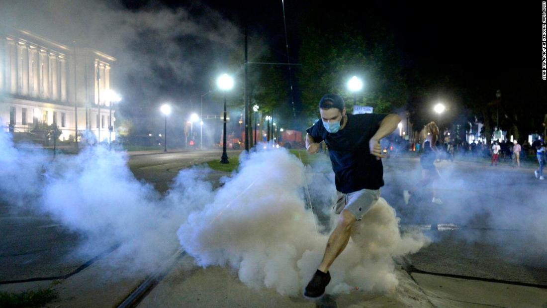 A man jumps over a tear-gas canister as he is fired upon with rubber bullets on August 23.