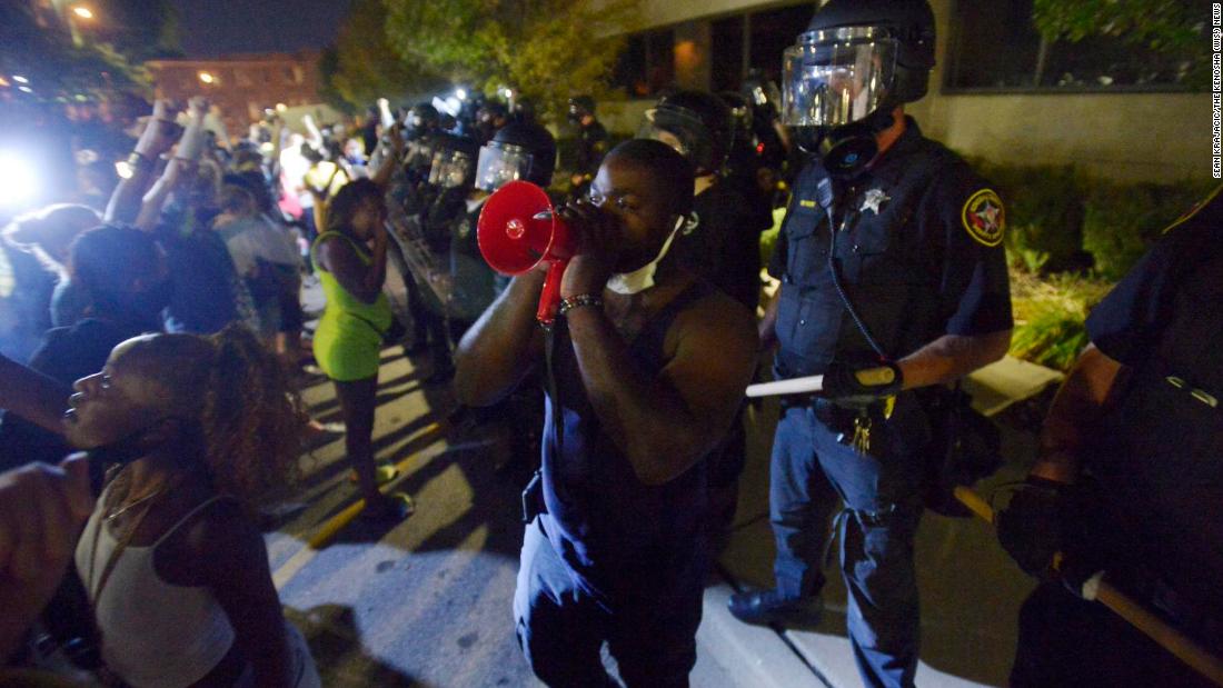 Demonstrators stand in front of a line of police at the Public Safety Building.