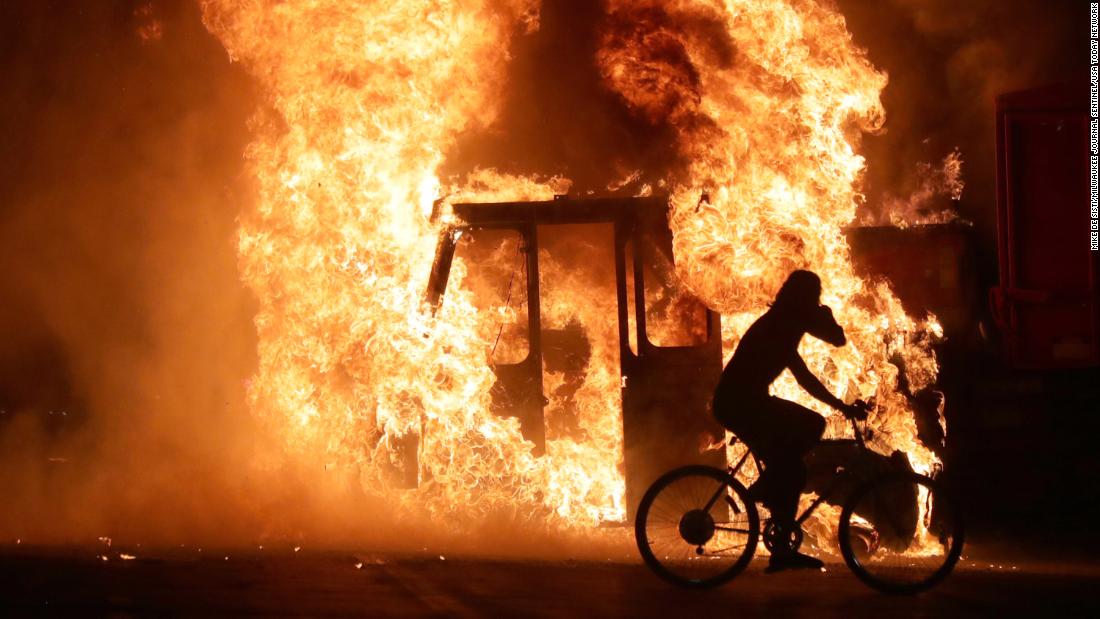 A man rides a bike past a city truck that was set on fire on August 23.