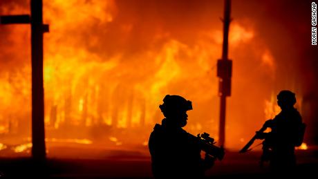 Police stand near a building that was on fire during protests Monday in Kenosha