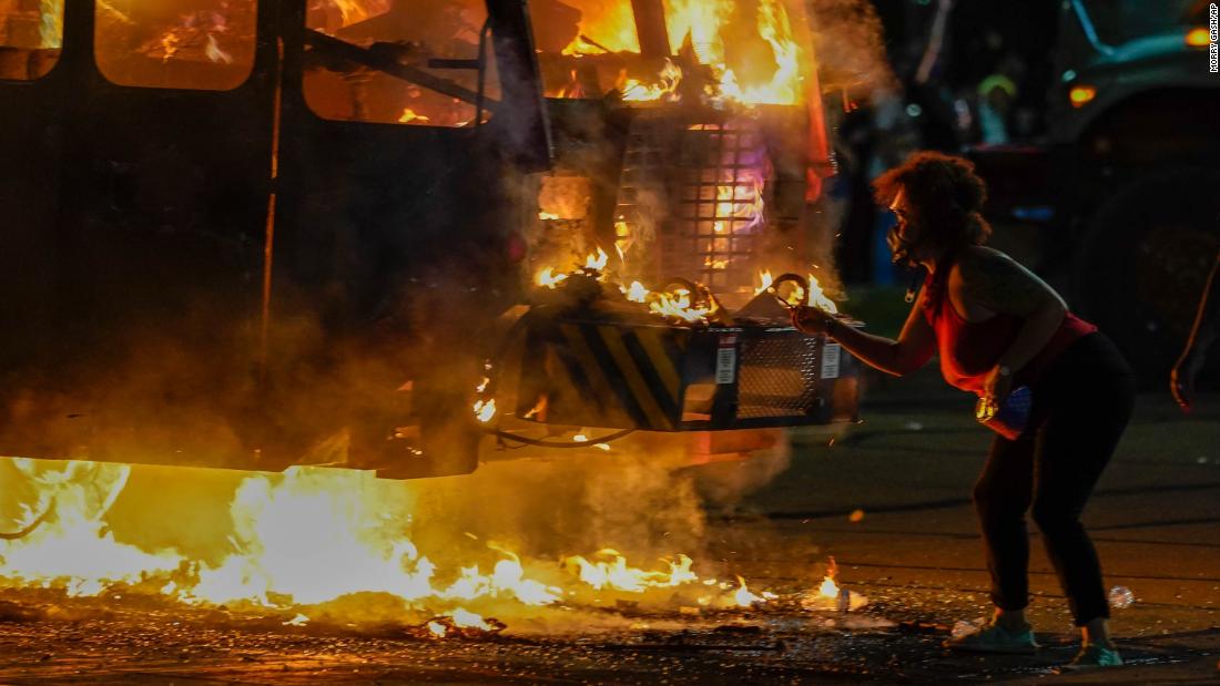 A protester lights a cigarette on a garbage truck that was set on fire during protests.