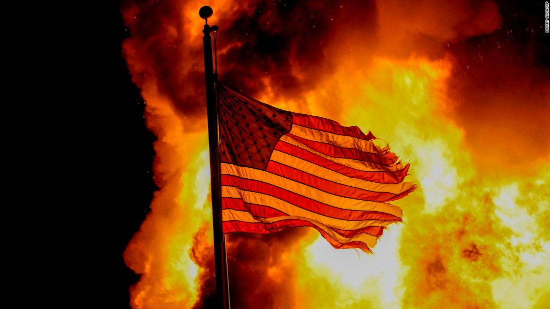 An American flag flies over a Department of Corrections building that was on fire during protests.